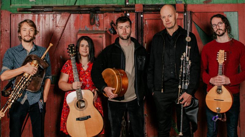 band with instruments stood against a wall 