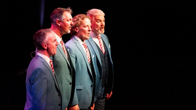The four memebers of 4 in a bar on stage performing
