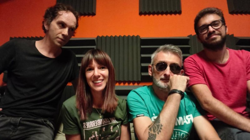 The members of Electric Blue, sitting in a recording studio, smiling at the camera