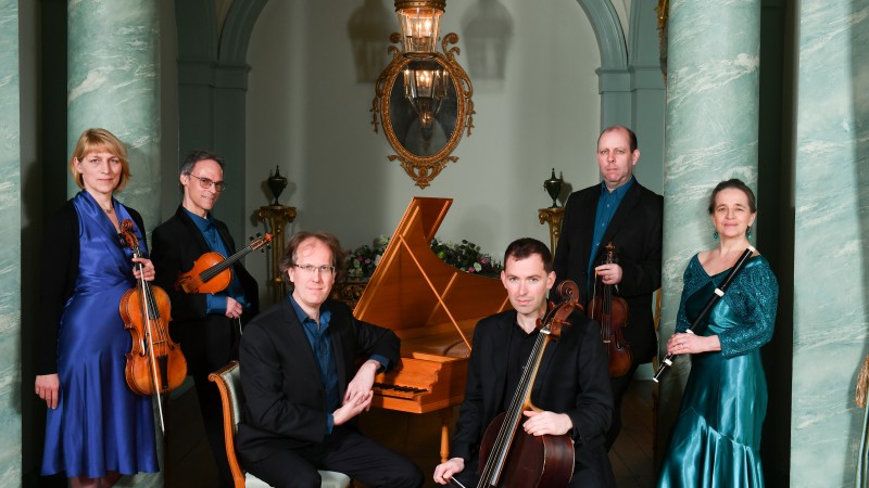 The members of London Handel Players smiling and posing with their instruments.
