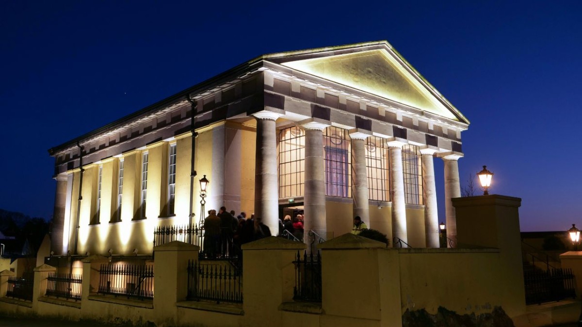 Exterior image of an uplit Portico on a clear night not long after dusk