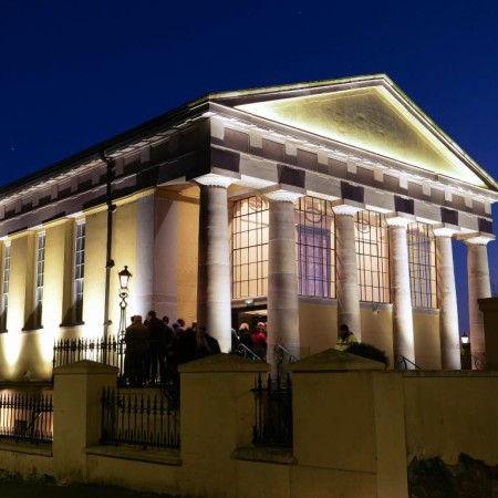 Exterior image of an uplit Portico on a clear night not long after dusk